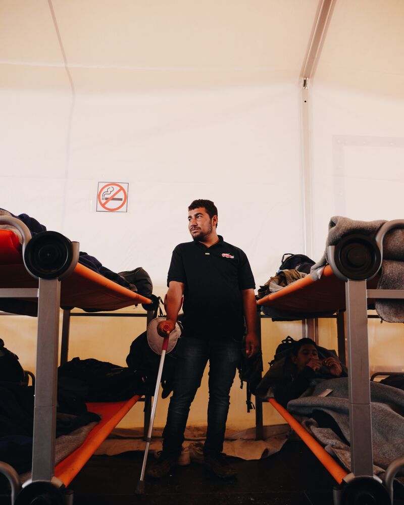 Man met kruk tussen bedden in één van de tenten van UNHCR.