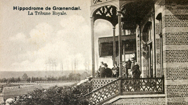 Koninklijke loge: op het terras bemerk je Leopold II en gasten. Aan de slagschaduwen zie je dat ze recht in het zonlicht staan.
