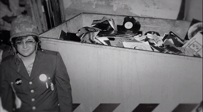 Steve Dahl, voor de gelegenheid als militair verkleed, naast de container met gesneuvelde platen