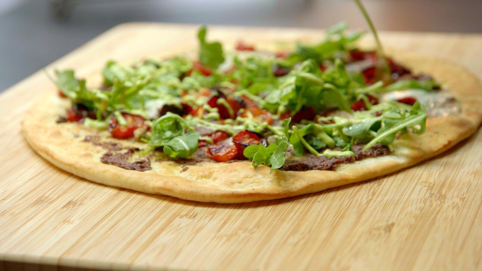 Pizza met tapenade van olijven, gekonfijte tomaten en basilicum aïoli
