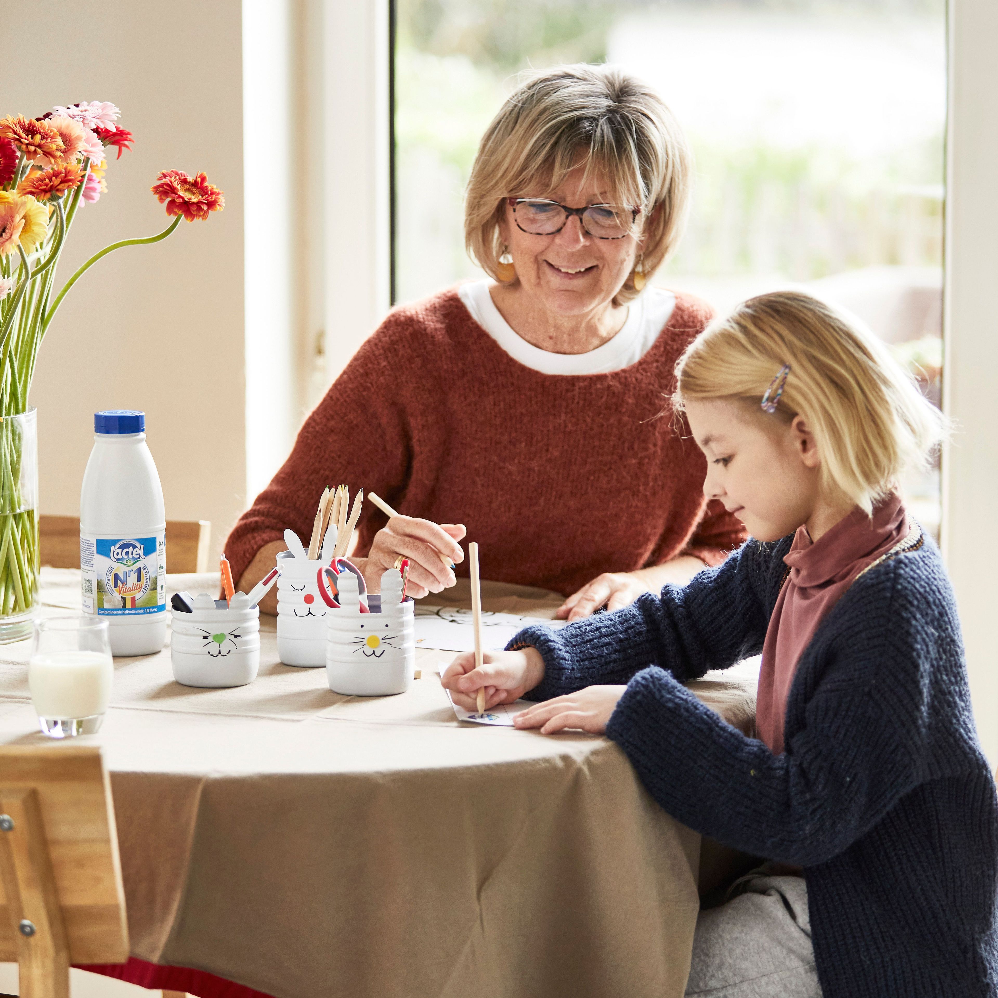 Oma met kleindochter aan de keukentafel met een glas Lactel N°1 melk