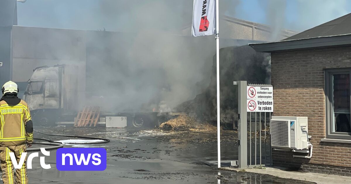 Vrachtwagen met aanhangwagen vol stro brandt uit bij bedrijf in
