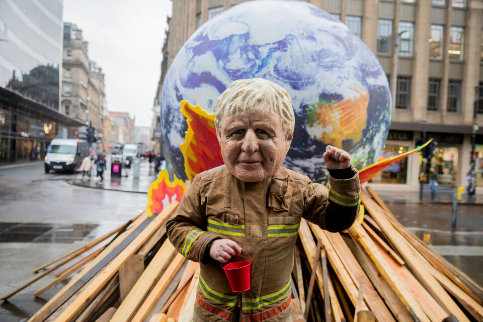 De wereld brandt maar de Britse premier Johnson krijgt het vuur niet geblust: de ngo Oxfam voerde vanmorgen een protestactie. 