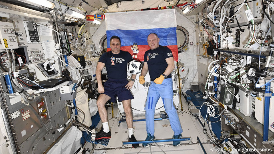 De Russen Anton Tsjkaplerov en Oleg Artemijev tonen de WK-bal in het ISS.