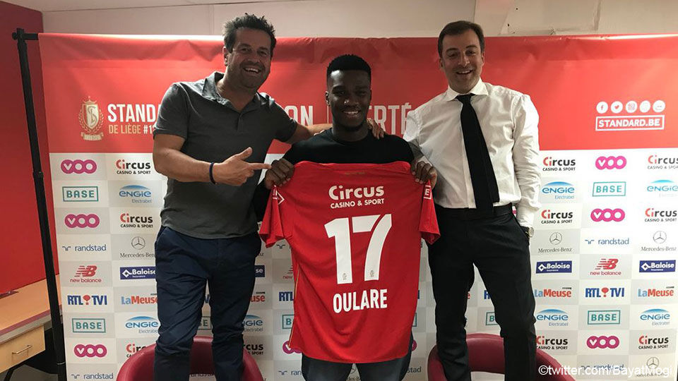 Oulare poseert met zijn nieuwe shirt van Standard, in aanwezigheid van zijn spelersmakelaar Mogi Bayat.