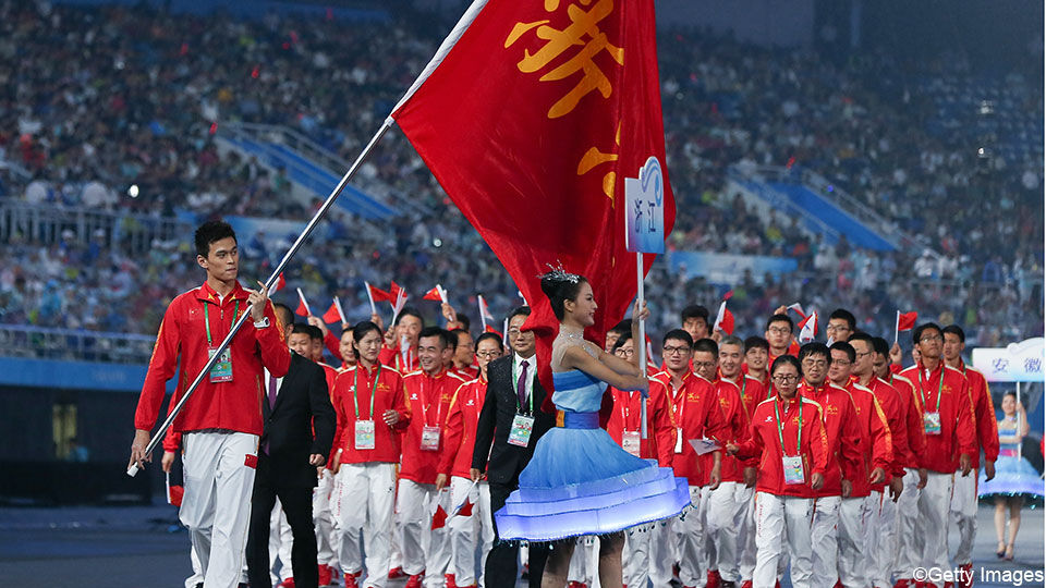 De Chinese delegatie betreedt de arena, met een vlaggendrager.