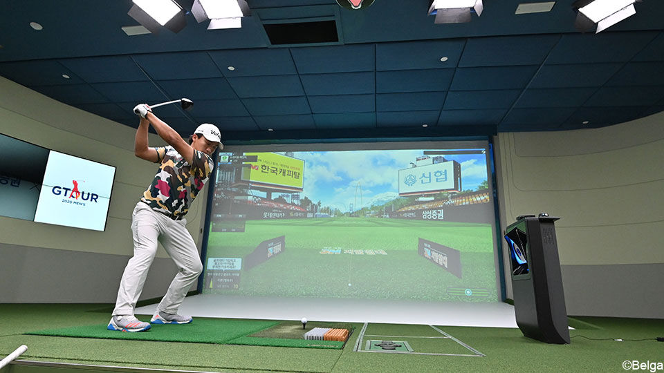 Een Zuid-Koreaanse screengolfer swingt zijn bal naar het scherm.