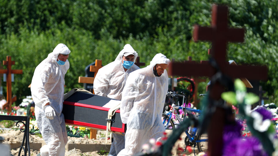Arbeiders in beschermingsmateriaal op een begraafplaats in Sint-Petersburg.