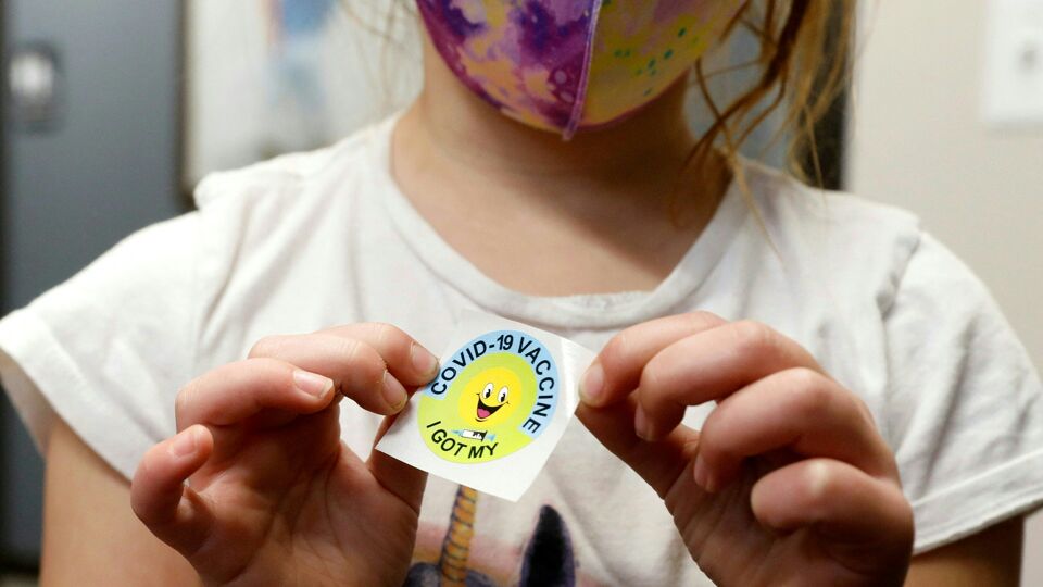 Een Amerikaans meisje toont een sticker die ze kreeg nadat ze gevaccineerd werd met het Pfizer-vaccin.