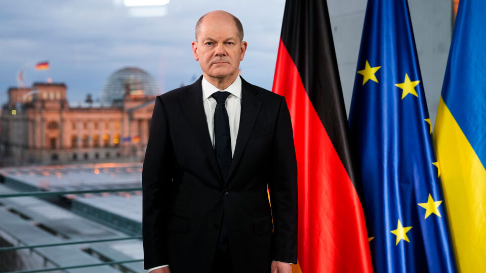 De Duitse bondskanselier Olaf Scholz bij de Duitse, Europese en Oekraïense vlag.