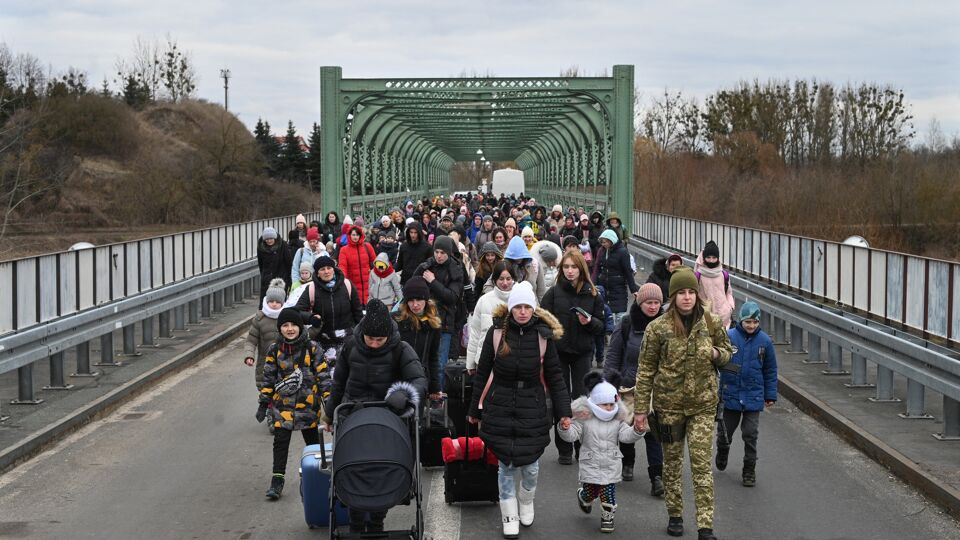 Vluchtelingen steken een brug over aan de grensovergang Zosin-Ustyluh