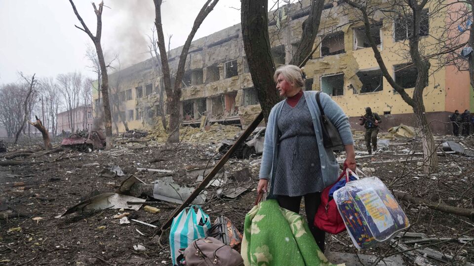 Een vrouw wordt weggedragen van het getroffen ziekenhuis in Marioepol