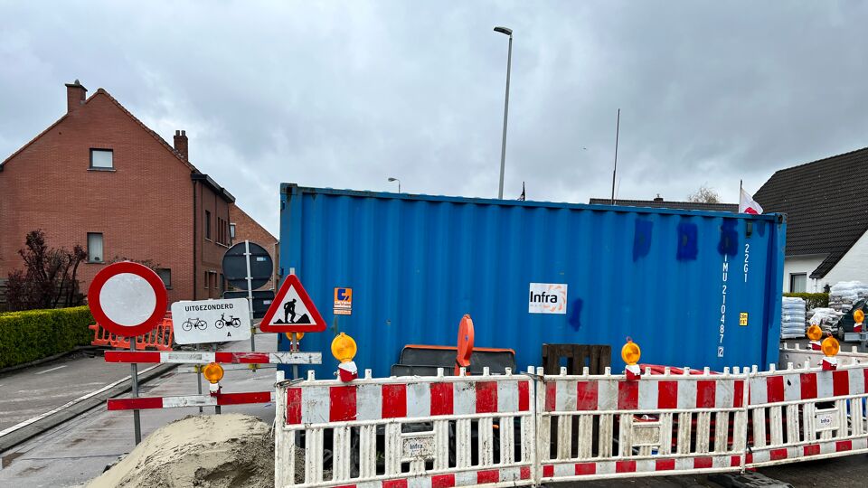 Een container en bergen zand in de Sint-Niklaasstraat in Sint-Gillis-Waas