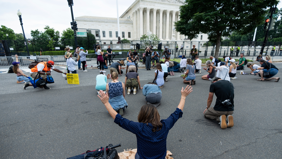 Medestanders van de ontslagen coach bidden voor het Hooggerechtshof.