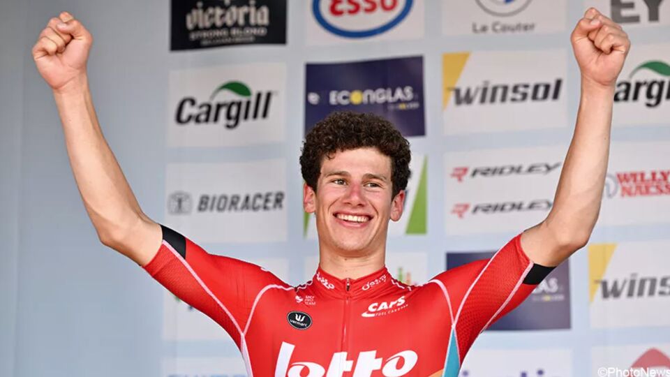 Alec Segaert staat met zijn handen in de lucht op het podium. 