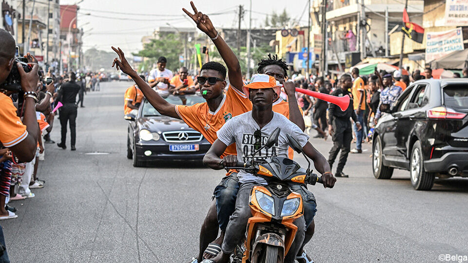 3 supporters zitten samen op een motor doorheen de stad te rijden.