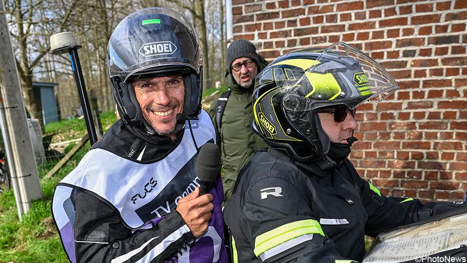 Philippe Gilbert achterop op de motor in de koers.