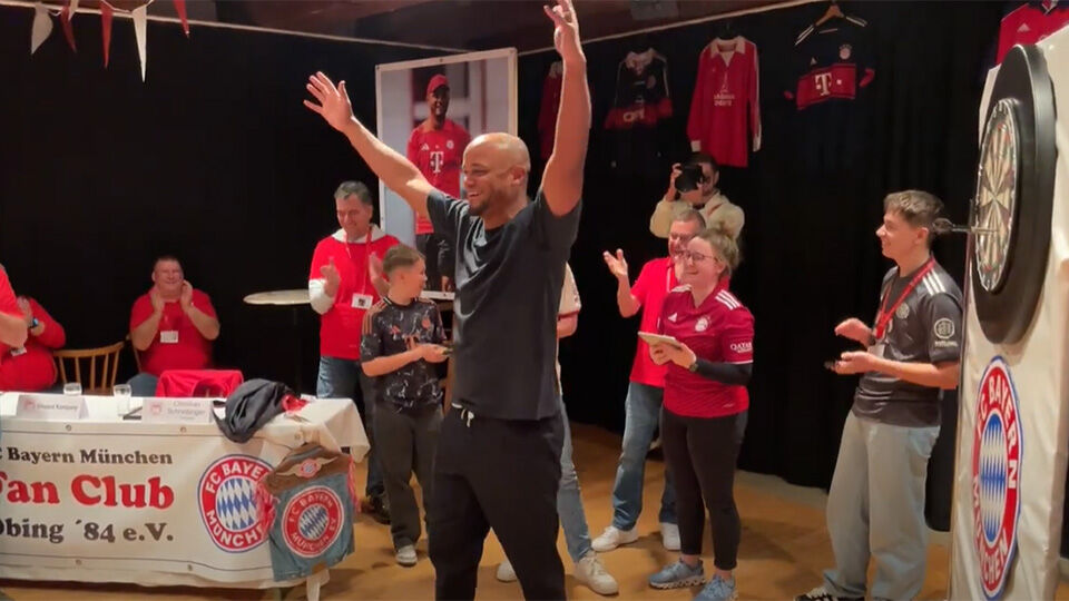 Vincent Kompany juicht na zijn zege in een potje darts tegen enkele fans.